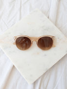 Clear round lens sunglasses laying on marble board. 