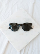 Black round lens sunglasses laying on marble board. 