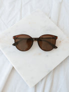 Brown round lens sunglasses laying on marble board. 