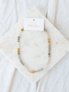 Round beaded necklace laying on marble board. 