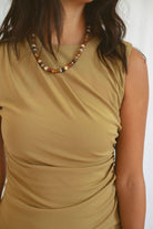 Model wearing sleeveless mini crew neck ruched dress in golden olive.