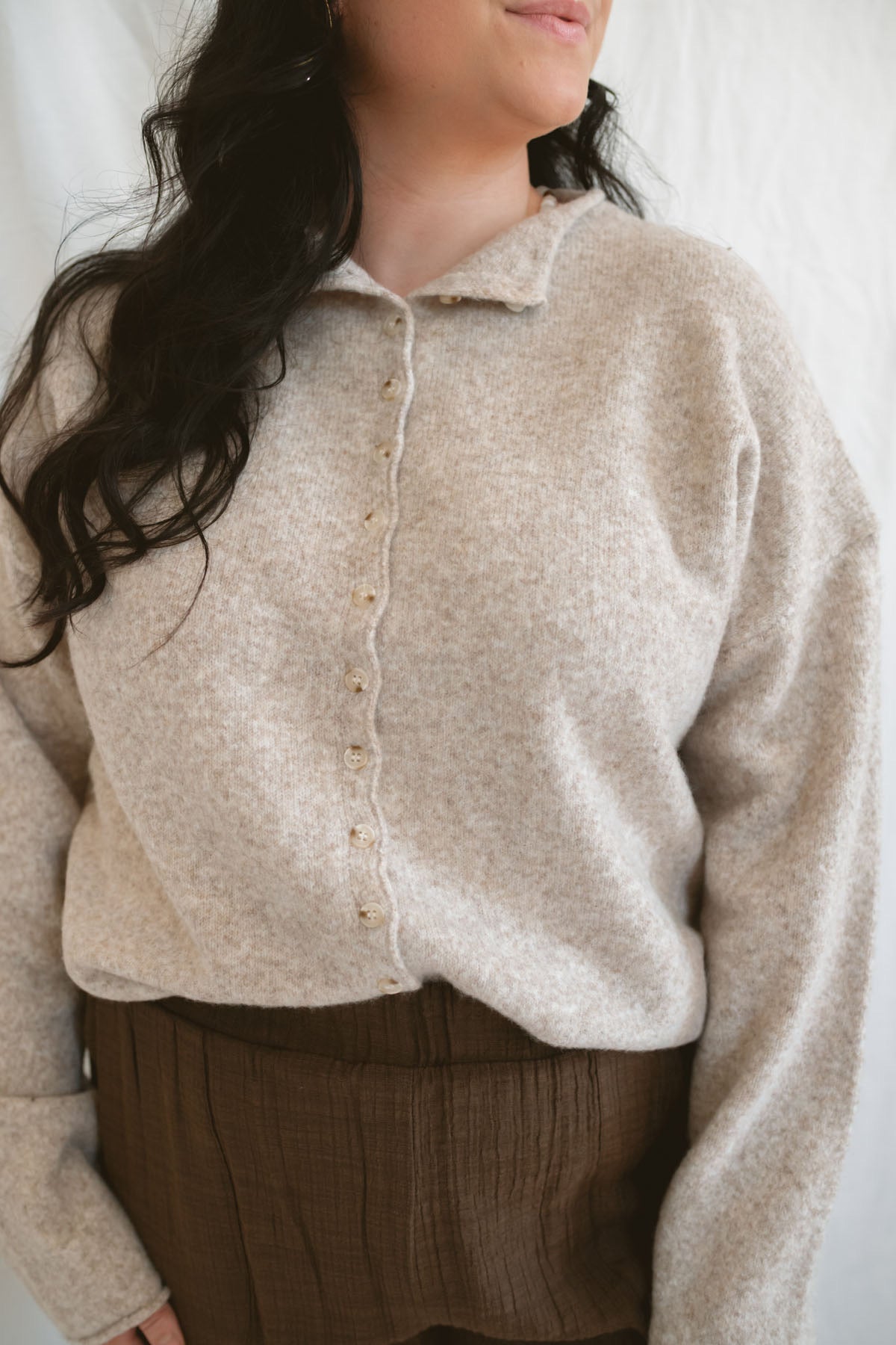 Model wearing full button up mock neck cardigan in oat.