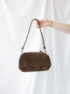 Model holding woven slouch bag with adjustable shoulder strap. 