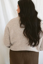 Model wearing full button up mock neck cardigan in oat.