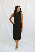Model wearing pleat detail black midi dress.
