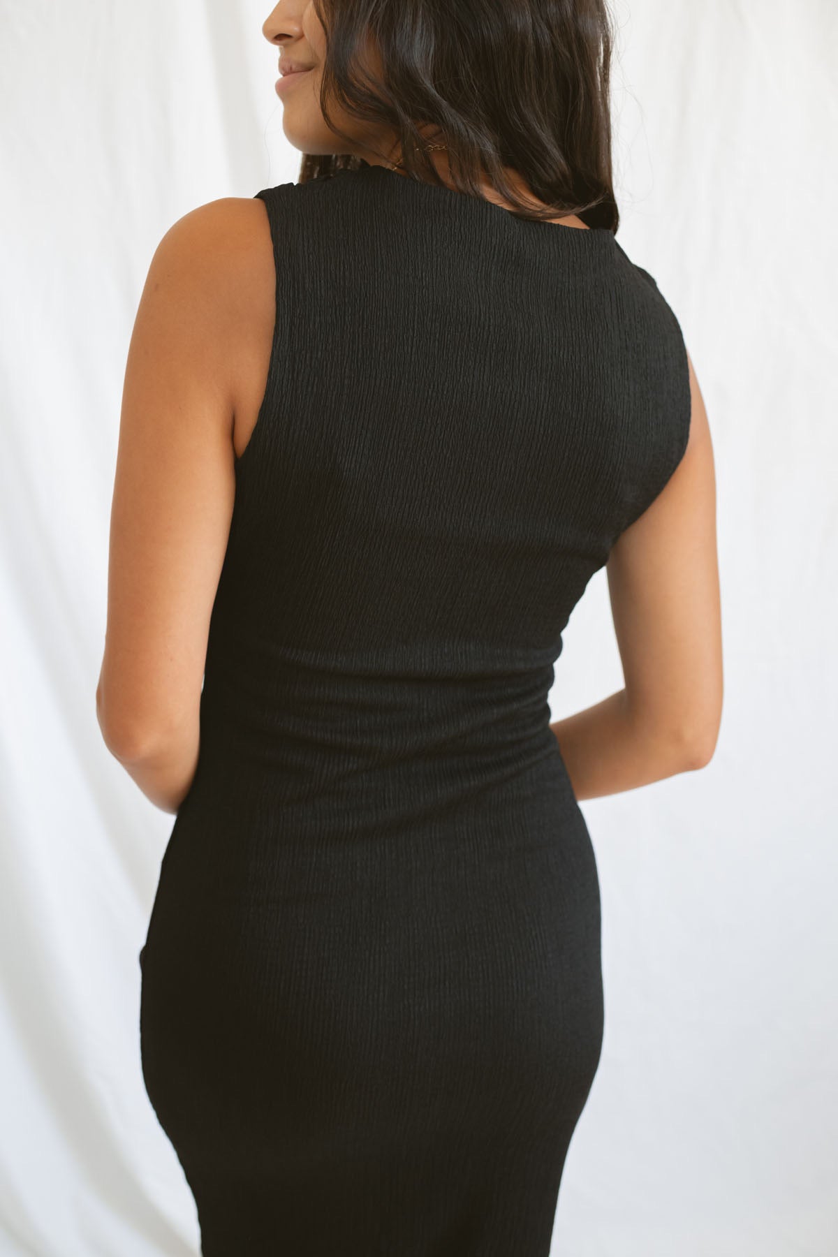 Model wearing pleat detail black midi dress.