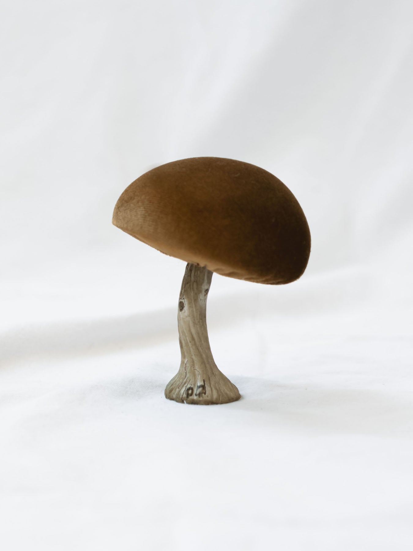 The olive color mushroom set up on a white linen backdrop. 