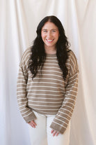 Selena taupe sweater with cream stripes, a relaxed drop shoulder fit, crew neckline, and long sleeves.
