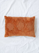Velvet rectangle pillow with leaf print laying on white linen backdrop. 