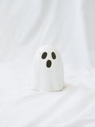 The smaller shorter style of the LED ceramic white ghost sitting on a white linen backdrop. 