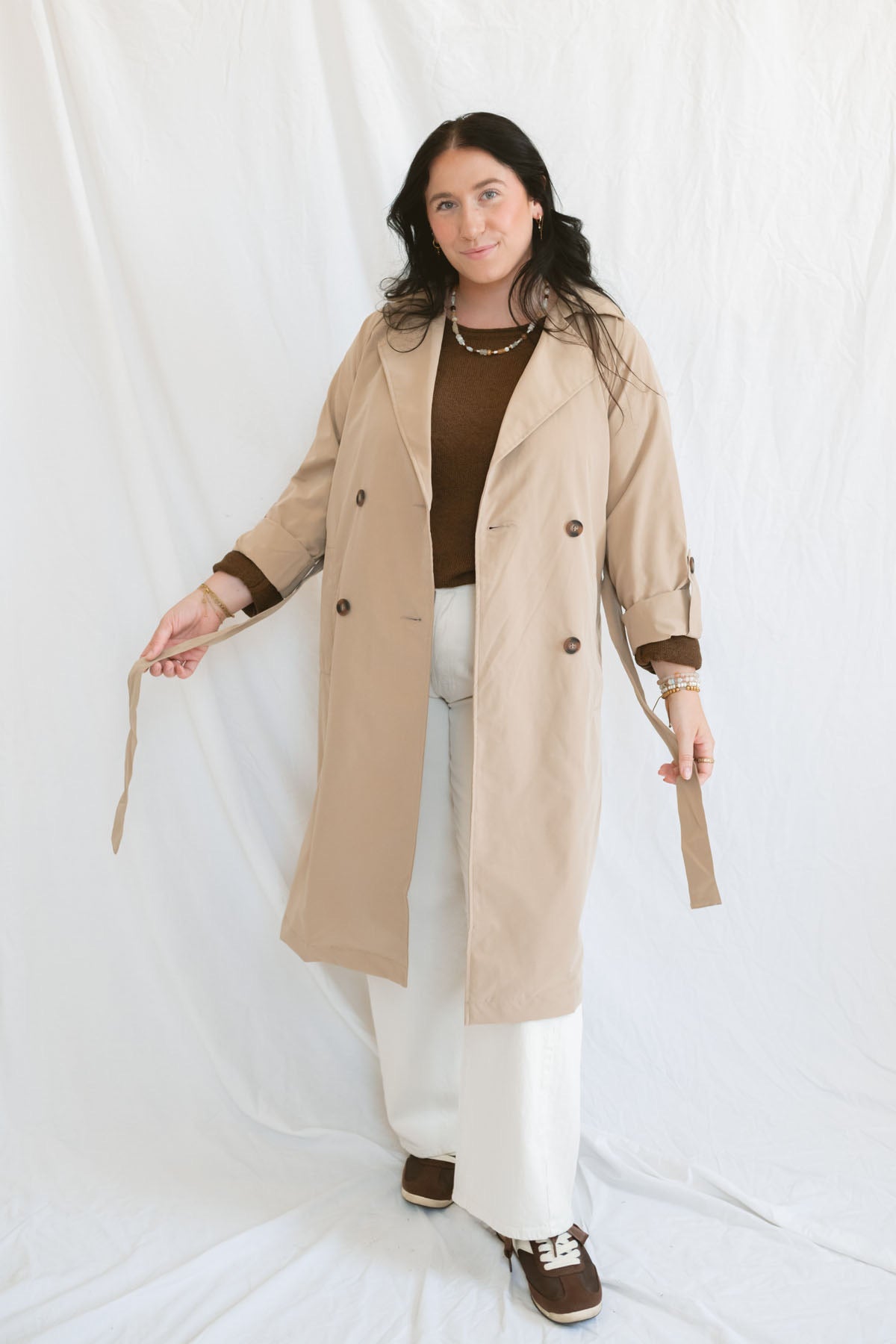 Model wearing the khaki long sleeve trench cost with buttons and belt.