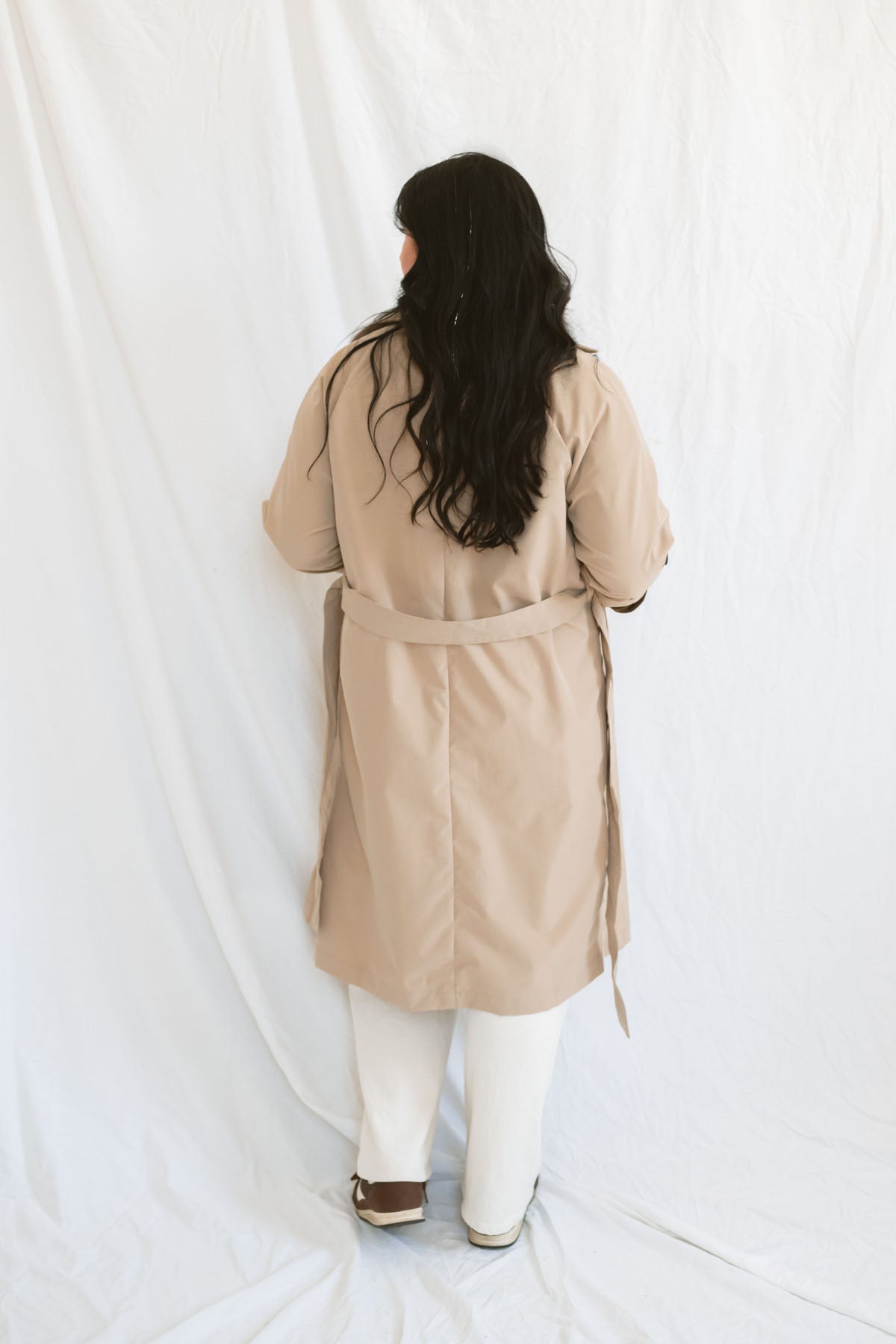 Model wearing the khaki long sleeve trench cost with buttons and belt.