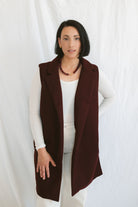 Model wearing the open sleeveless notched collar vest in burgundy color.