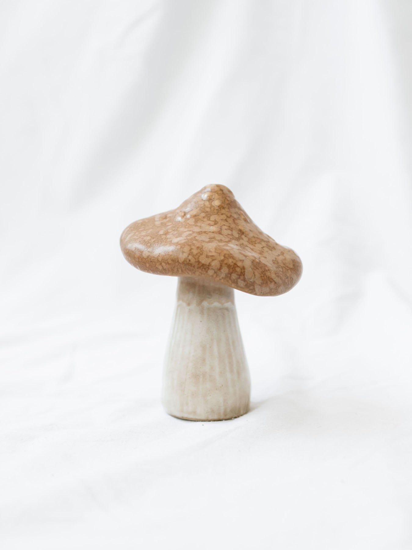 Close up of the large stoneware mushroom sitting on a white linen backdrop. 