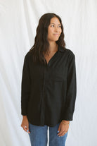 Model wearing classic black button up styled fully buttoned with a classic denim.