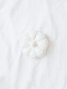 Top view of the white ceramic textured pumpkin shown sitting on white linen backdrop. 