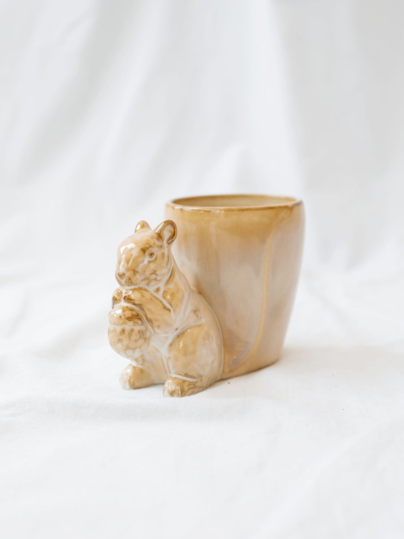 Squirrel detail mug/vase sitting on white linen backdrop. 