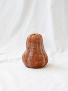 The gourd shaped LED candle sitting on a white linen backdrop. 