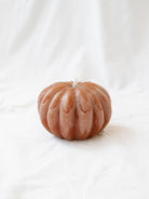 The Pumpkin shaped LED candle sitting on a white linen backdrop. 