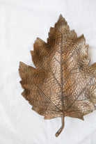 Antique gold leaf dish laying empty on a white linen backdrop.