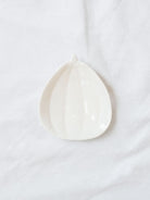Mini stoneware pumpkin dish in white sitting on a white linen backdrop. 