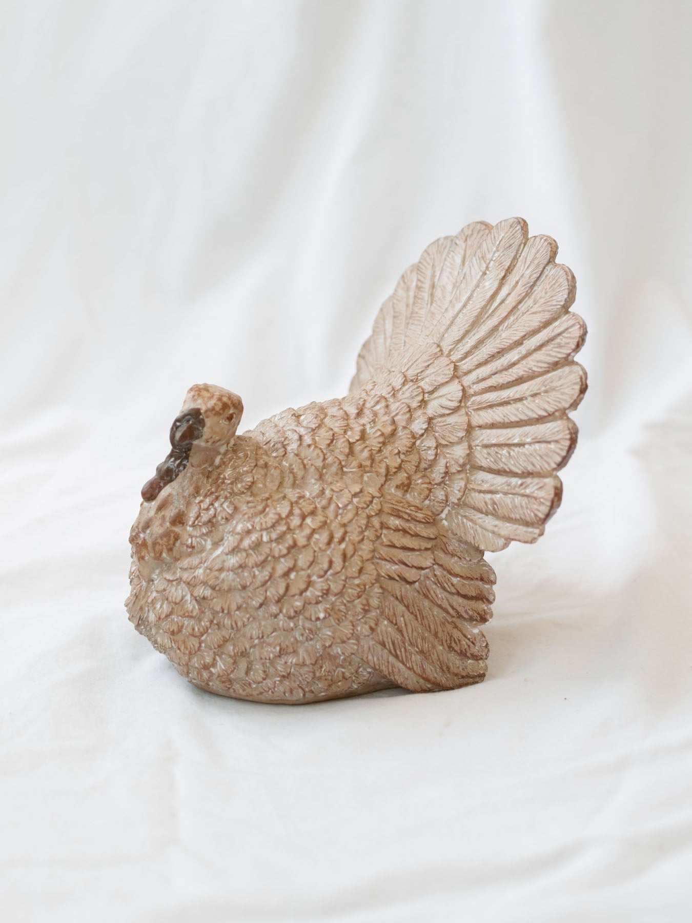 Resin tabletop turkey sitting on white linen backdrop. 