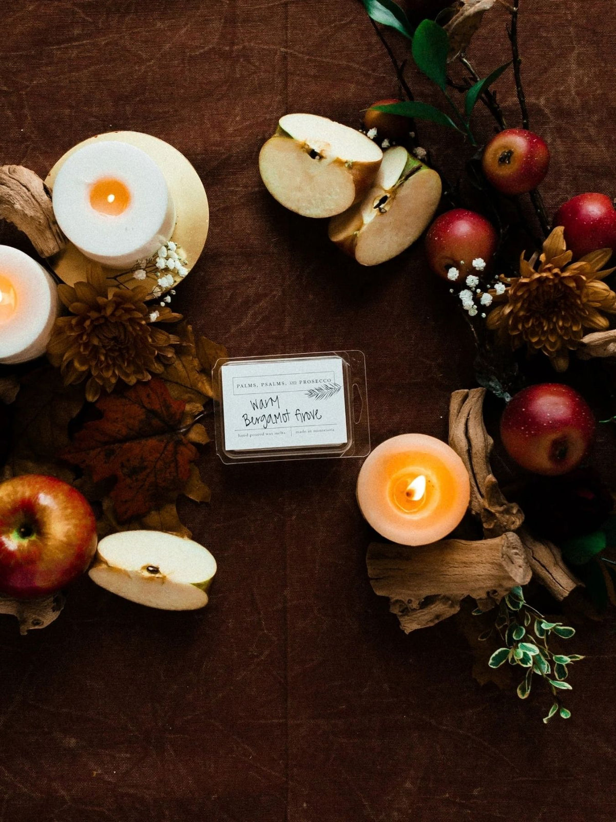 White wax melts on a brown background with apples, candles and other fall floral and decor 