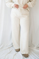 Woman wearing a light beige lounge set with crew neck sweatshirt and drawstring pants on a white background 