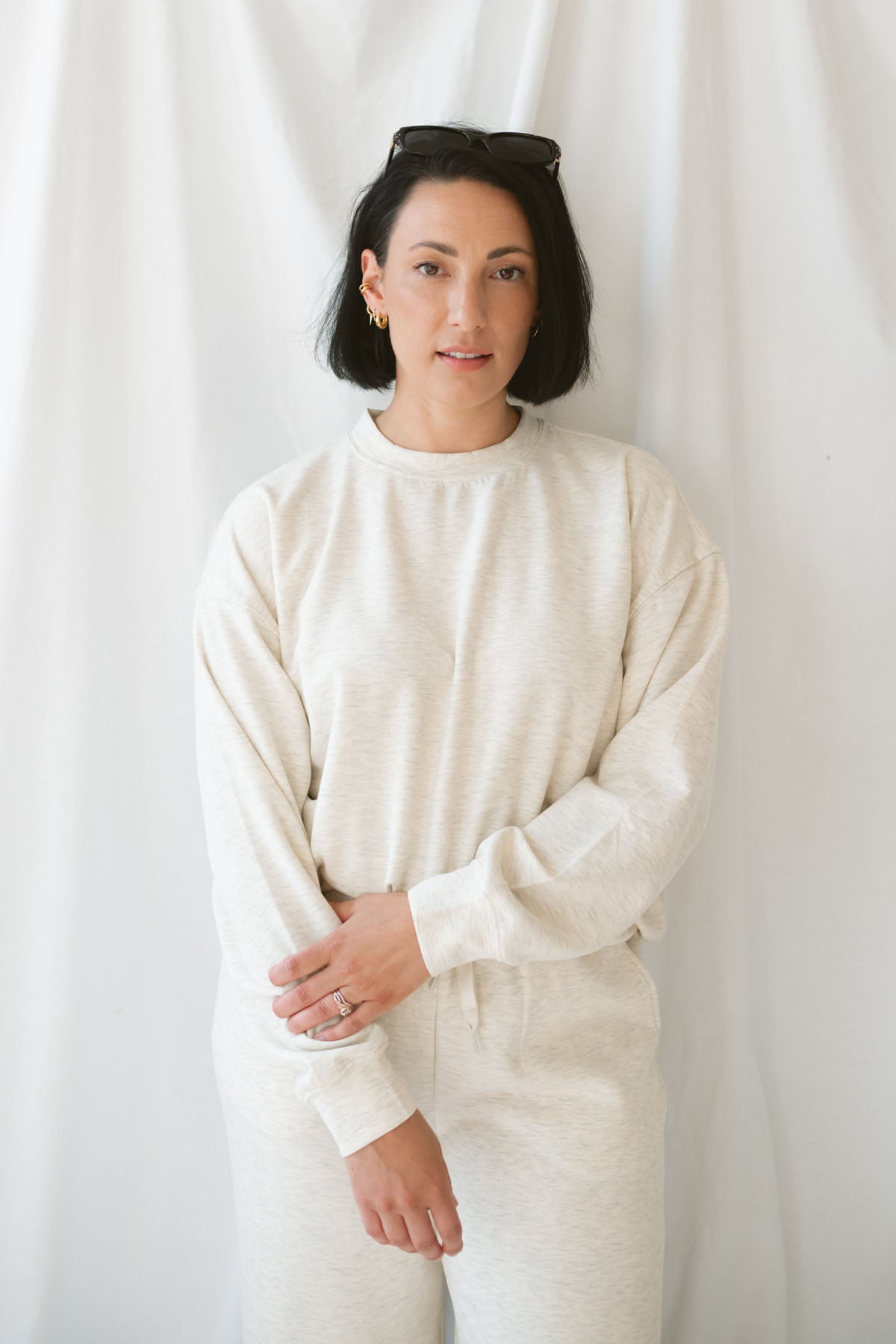 Woman wearing a light beige lounge set with crew neck sweatshirt and drawstring pants on a white background 