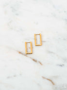 Rectangle hoop earring with stud post in gold laying on white marble board. 
